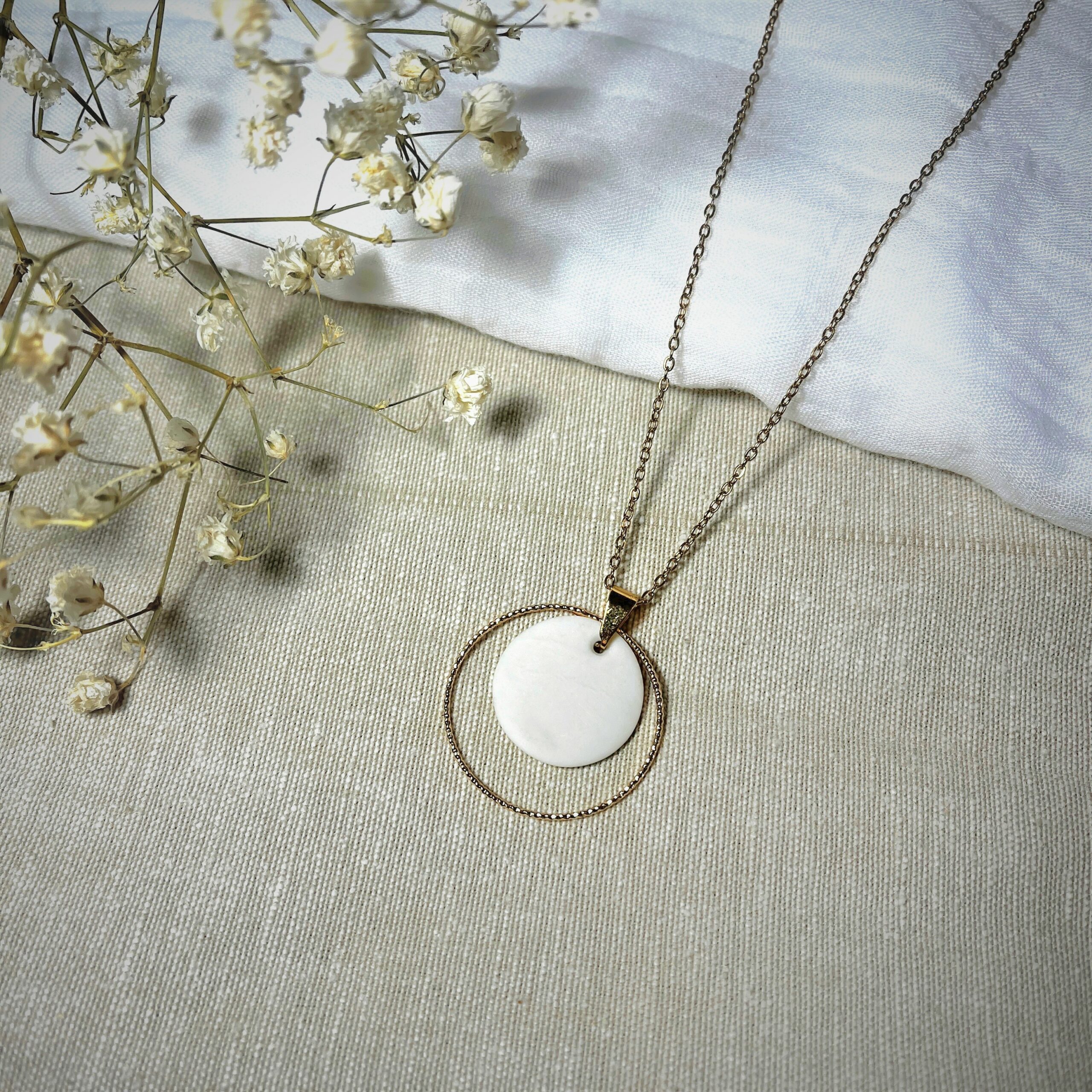Médaillon de 2cm de diamètre en porcelaine blanche entouré d'un anneau doré de 3 cm vendu avec sa chaine dorée de 45cm de longueur